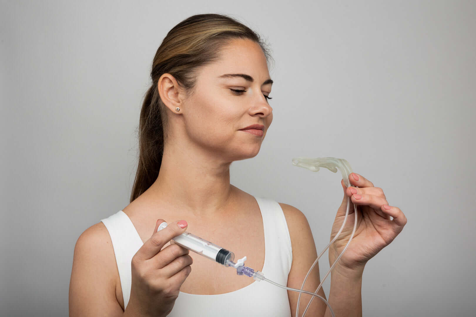 Woman demonstrating the Isences® TMD Physio Care™ high-resistance jaw mobility device for TMD rehabilitation device.