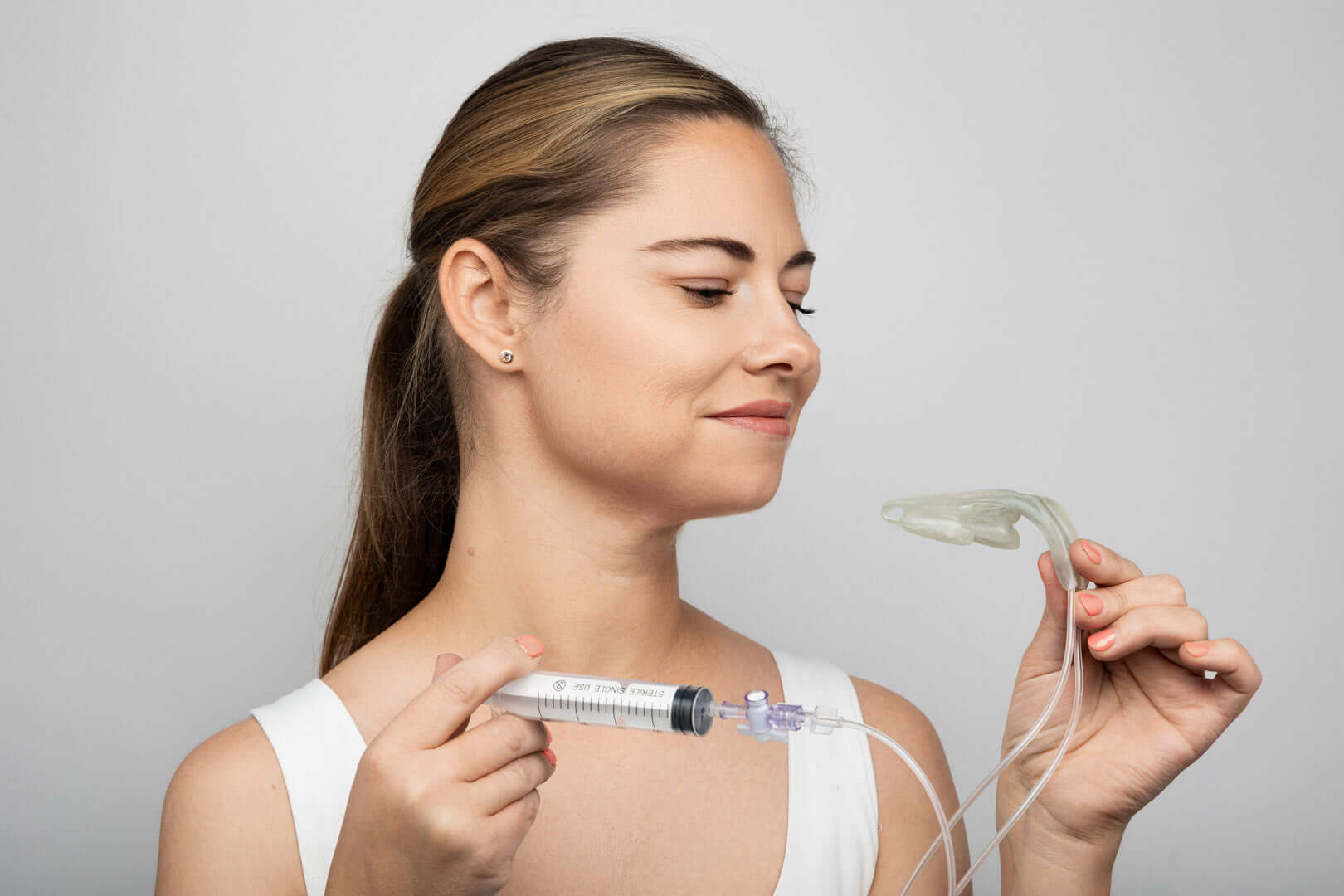 Woman demonstrating the Isences® Jaw Physio Care™ jaw mobility exercise device for rehabilitation.