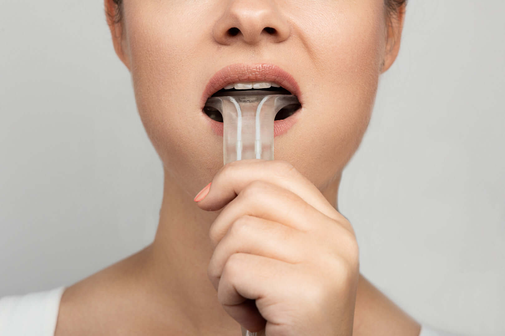 Woman using Isences® TMD Physio Care™ high-resistance TMD rehabilitation device for jaw exercise.